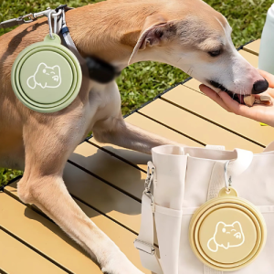 Hopfällbara Hundskålar och Vattenskålar – Portabla reseskålar för hundens mat och vatten Hund äter godis utomhus med koppel och grön hopfällbar skål; beige skål fastsatt på vit väska i bakgrunden.